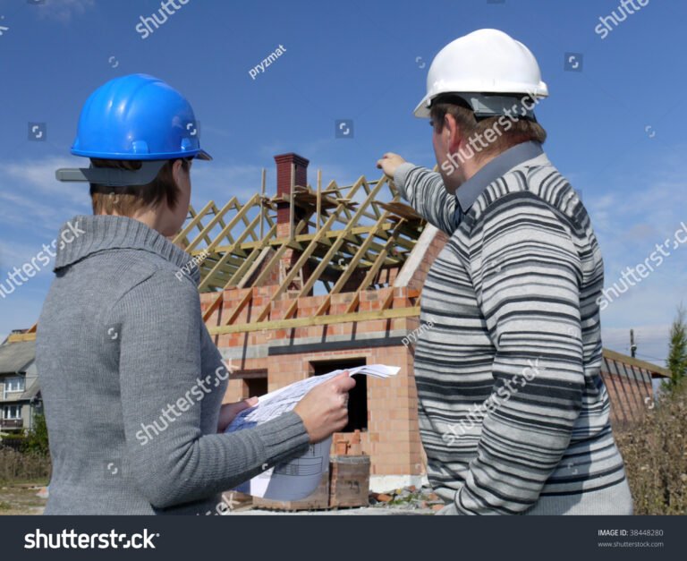 operai edili con caschi e piani di costruzione