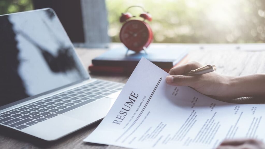 persona che scrive curriculum con laptop